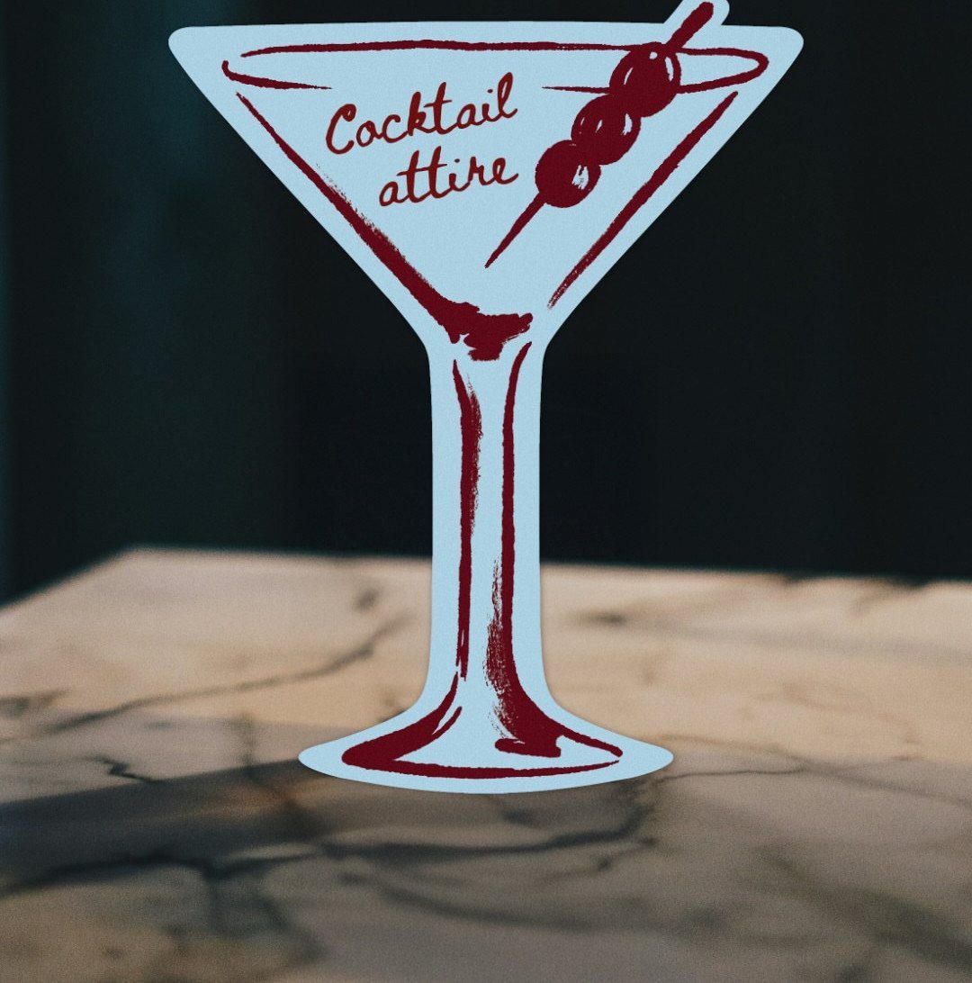 Martini glass shaped card with red text saying Cocktail attire on marble surface