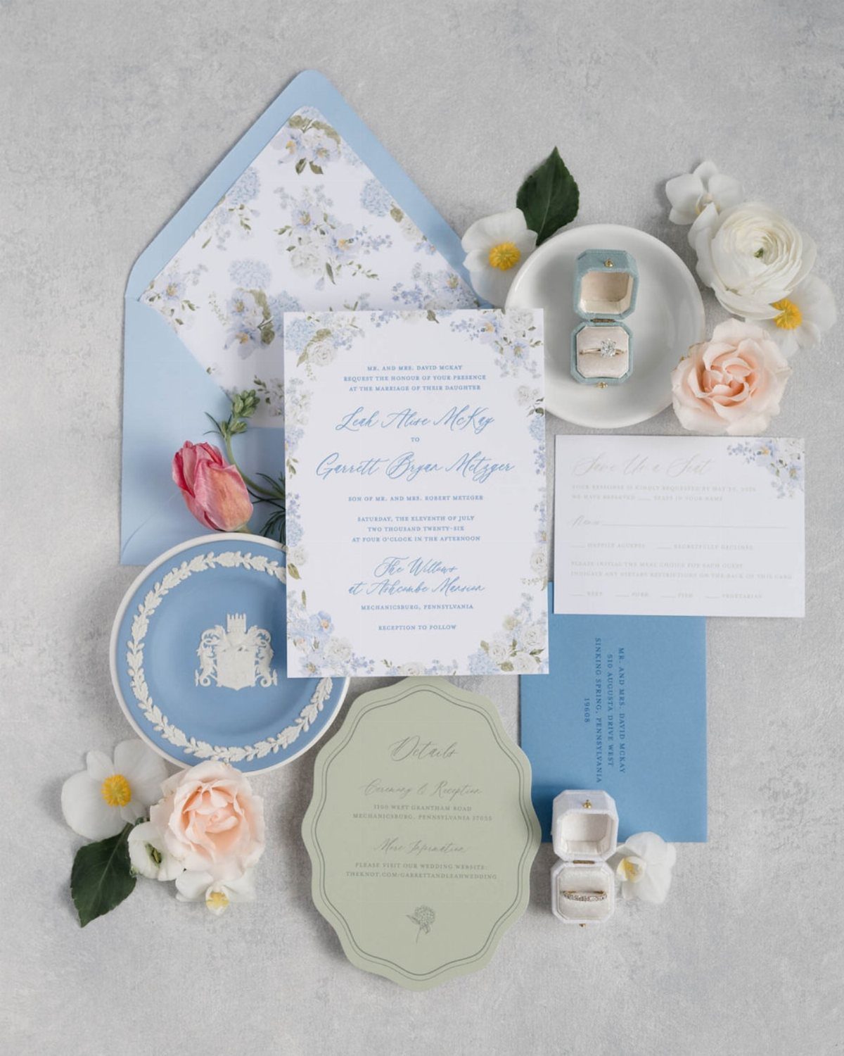 Wedding invitation suite with blue and green cards, floral accents, and elegant script fonts.