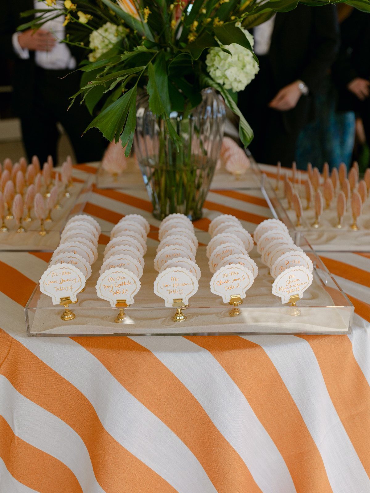 White scalloped place cards with gold script on a striped orange tablecloth