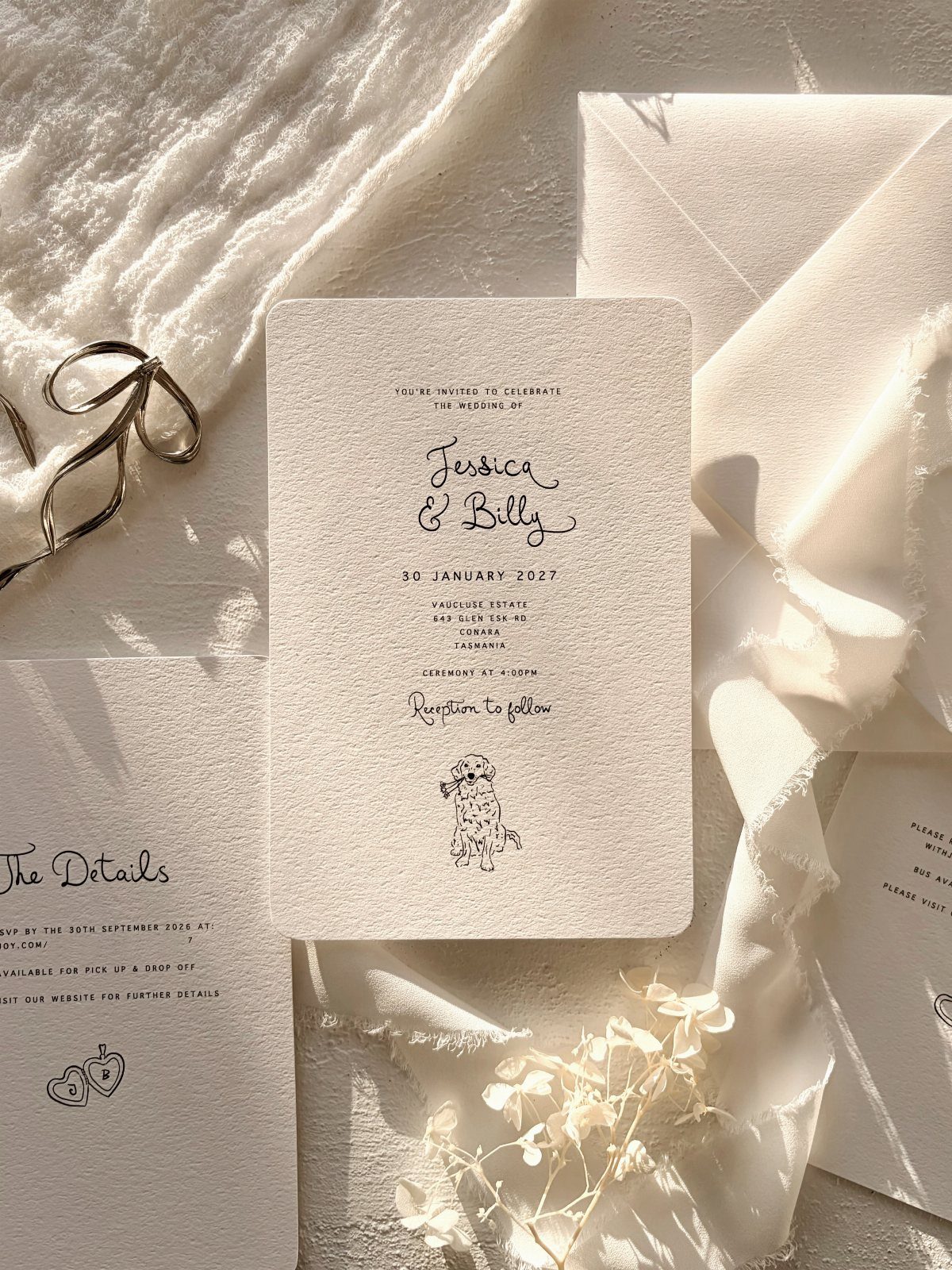 Handmade paper wedding invitation suite with deckle edges on white fabric and flowers