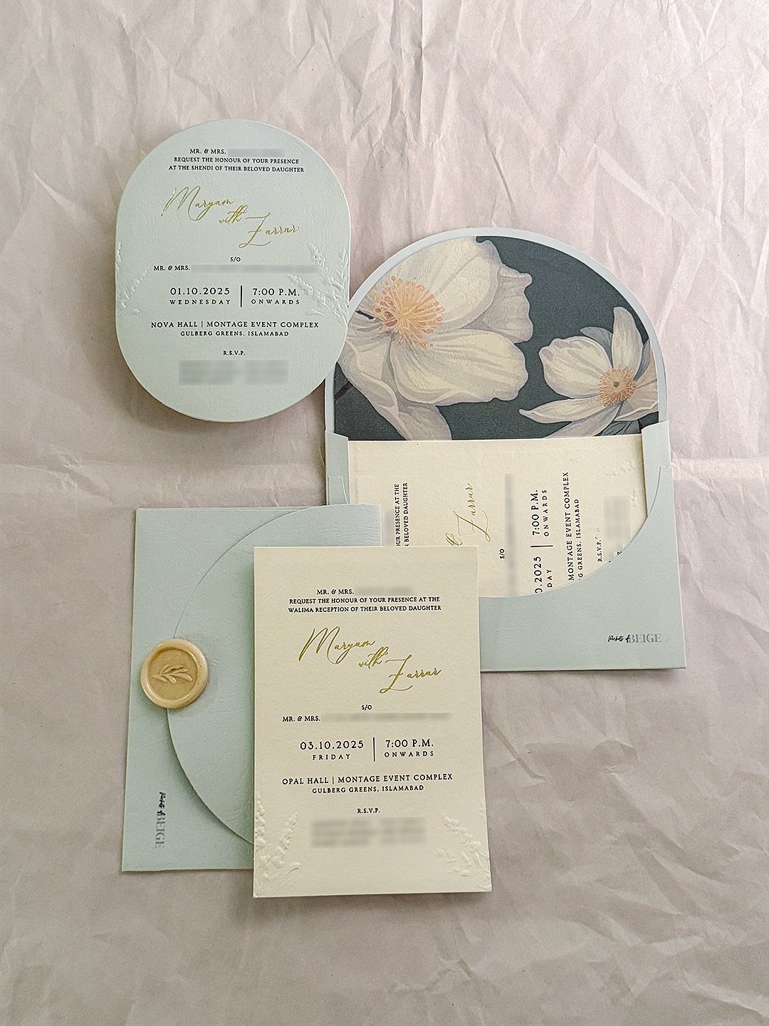 Wedding invitation suite with rounded corners and arched cards on white wrinkled fabric.