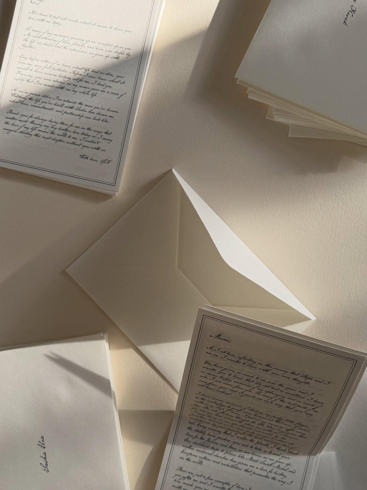 White wedding invitation cards and an open envelope on a beige surface.