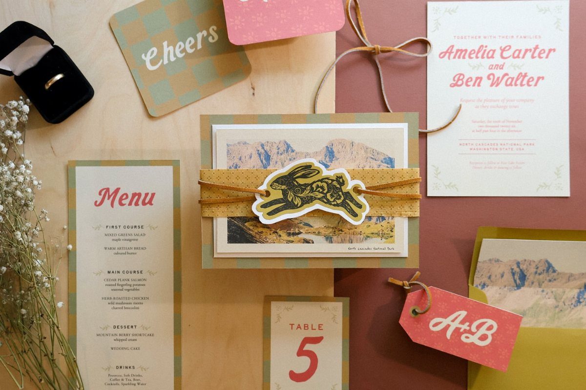 Wedding stationery suite with menu and invitation arranged on a light wooden plank surface.