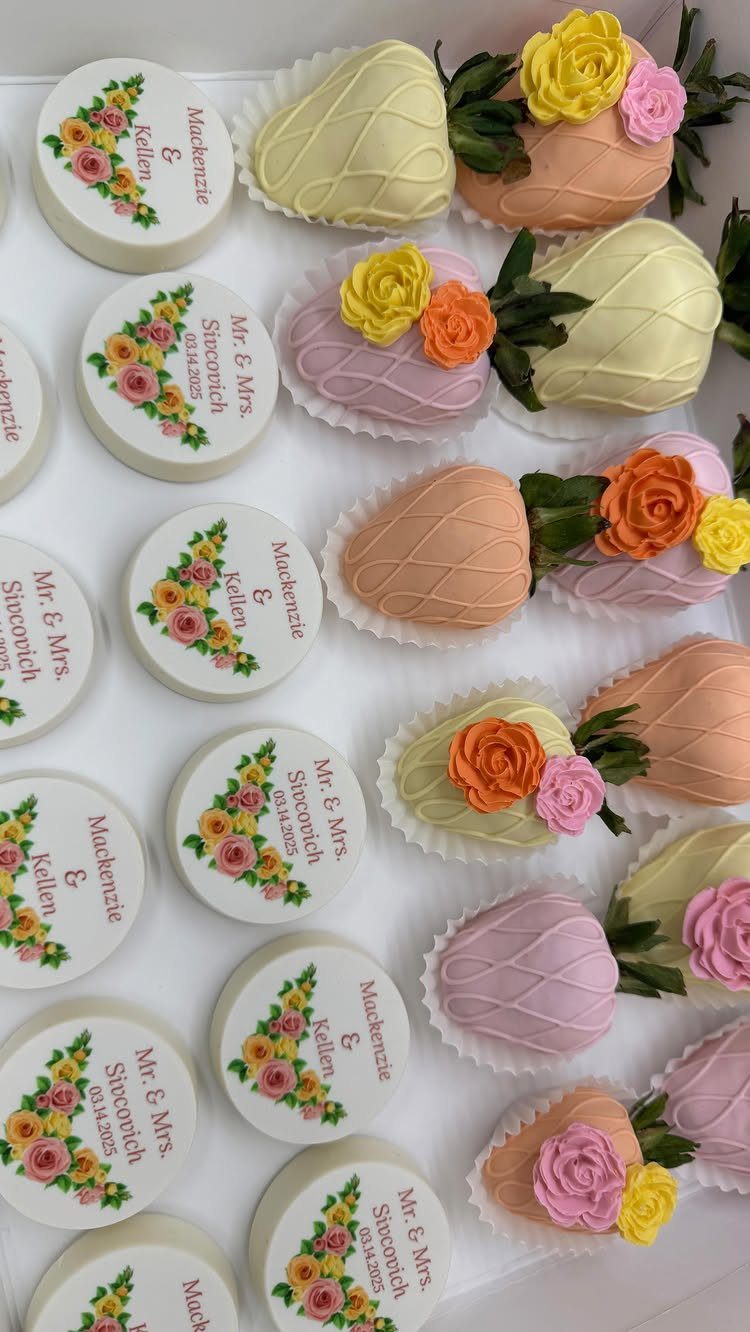 Decorated chocolates and pastel chocolate-covered strawberries with frosting roses on a white tray.