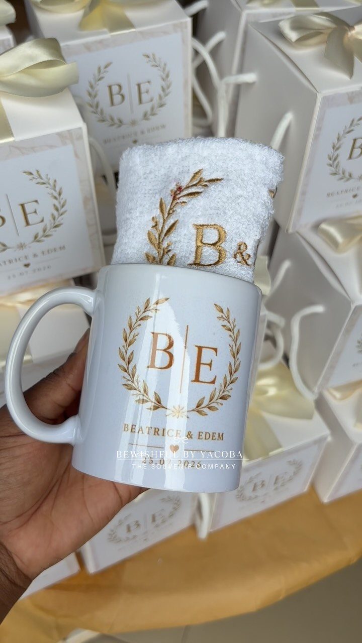 White ceramic mug and towel with gold wedding logos held before gift boxes.