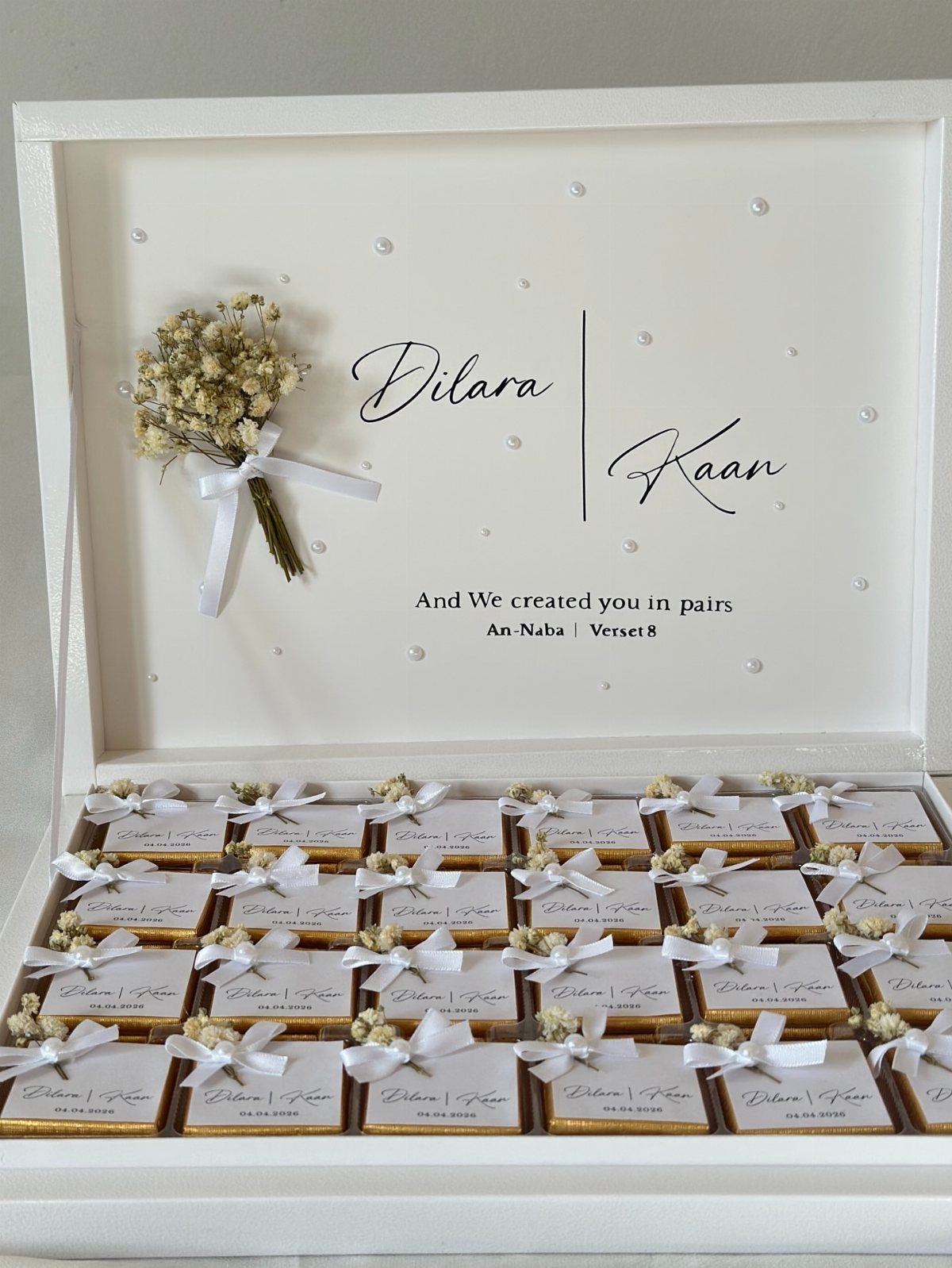 White gift boxes with ribbons and dried flowers inside a personalized wedding box.