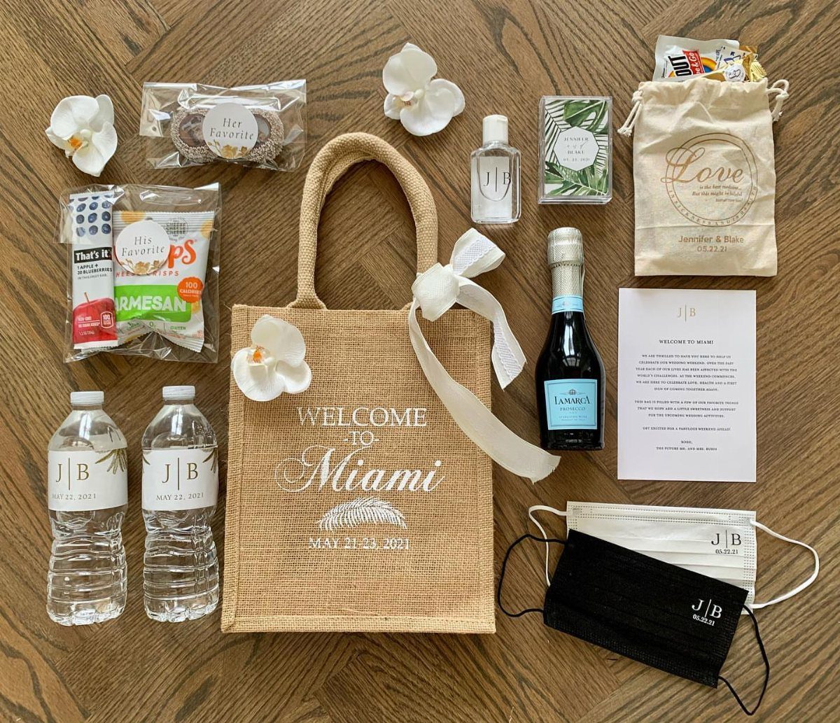 Personalized jute tote bag surrounded by wedding welcome bag items on wooden floor