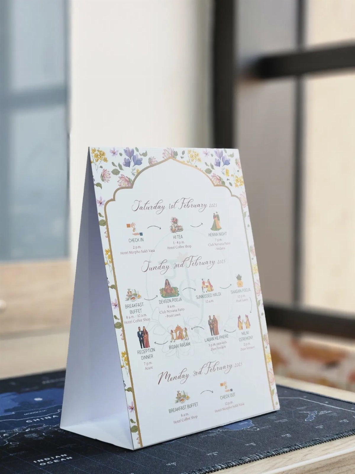 A-frame wedding itinerary card with floral borders and a detailed event schedule.