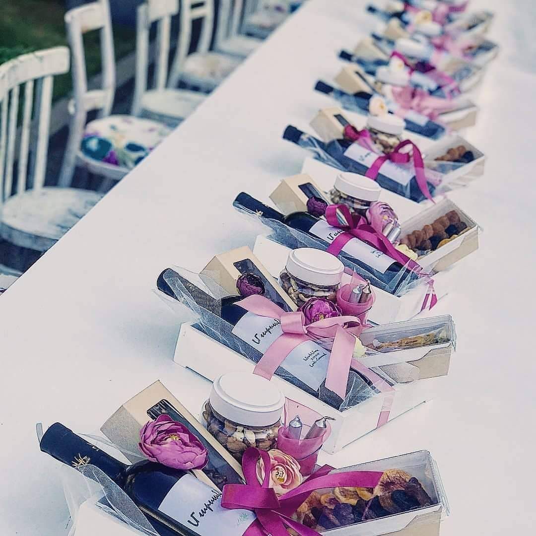 Wine wedding favor gift boxes with pink ribbons and small jars on a table